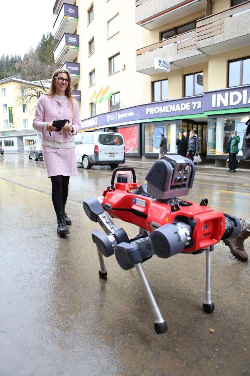 Kateryna Portmann walking alongside a quadruped robot on a street in Davos