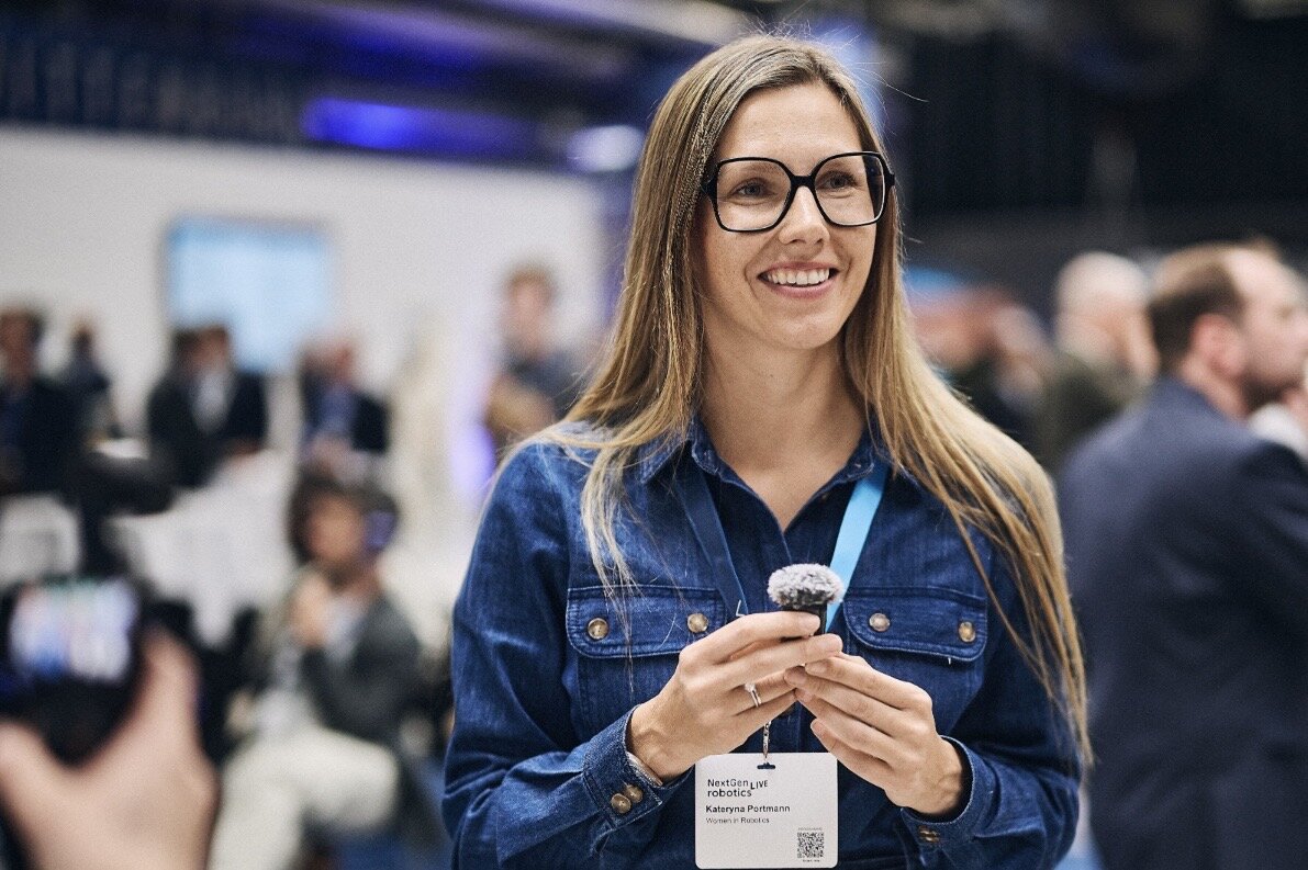 Portrait of Kateryna Portmann at the NextGen Robotics Live event, wearing glasses and a denim shirt